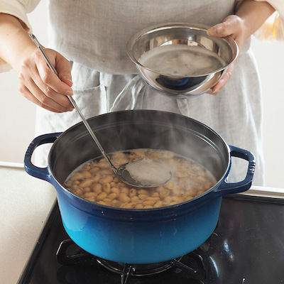 大豆を茹でます。豆が踊らないよう煮立たせず茹でるのがポイント。茹で上がりの目安は親指と薬指でつまんで大豆が潰せるくらい。茹で上がったら大豆と煮汁に分けて粗熱を取り煮汁(種水)は捨てずに取っておきます。
