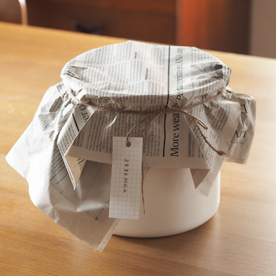 隙間なく詰めたら空気に触れないよう表面にラップを敷き、その上に塩などが入った袋を重石としてのせカビの発生を防ぎます。呼吸を妨げないように新聞紙で蓋をして風通しの良い場所で保管。完成は約半年後。