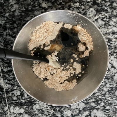 黒豆の煮汁と菜種油を加え、粉っぽさがなくなるまでゴムベラで混ぜます。