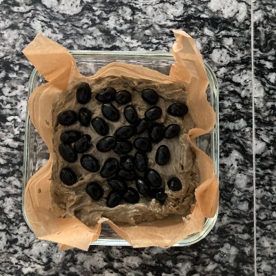 クッキングシートをひいた耐熱容器に生地を流しいれてならし、黒豆をのせます。