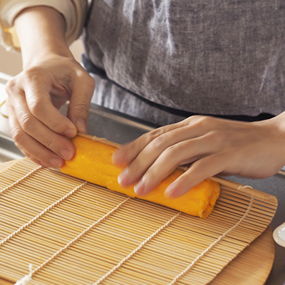 玉子焼きは熱いうちに巻きすの凹凸のある方を内側にして巻いて、輪ゴムで止めます。こちらは卵二個分で作りました。粗熱がとれたら1cmほどの厚さにカットします。