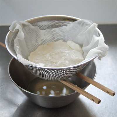 水切りヨーグルトを作る。ザルにキッチンペーパーを敷きヨーグルトを入れて2時間以上水を切る