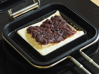 常温のホットパンにバターを置き、弱火で溶かしながら全体にバターを行きわたらせ、パンをホットパンの中心に置き、あんことクリームチーズを乗せもう一枚でサンドする。