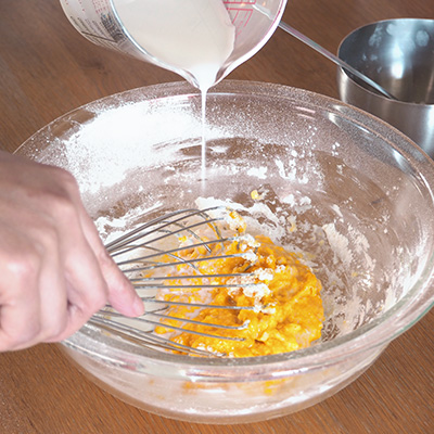 卵をほぐしながら、粉っぽさがなくなるまで混ぜます。粉がまとまったら、牛乳を少量ずつ加えそのつど混ぜます。