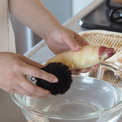 新生姜をスライスしやすい大きさに切り分け、茶色い皮の部分をたわしを使ってこそげとります。