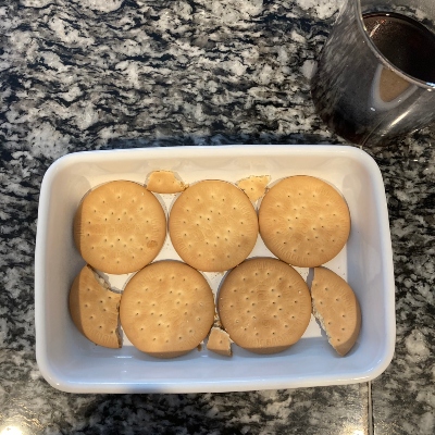 ホーローバットにビスケットを並べ、コーヒーをかけてしみこませます。