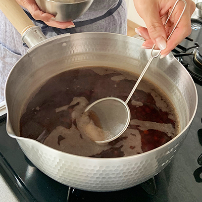 沸騰してアクが出てきたら取り除き、火を弱め40分から1時間半ほどゆでます。豆の大きさ、鍋、火加減によりゆで時間は異なります。指の腹で潰せるくらいの柔らかさになったら、ざるにあげてゆで汁を捨てます。