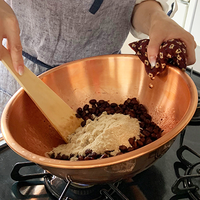 小豆を鍋に戻して砂糖を加え混ぜます。今回は熱伝導率が良く、色鮮やかに仕上がる銅鍋を使います。砂糖は数回に分けて入れると混ざりやすいです。